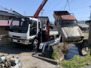 クレーンで吊り上げられて小川をまたぐダットサントラック
